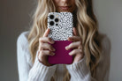 Lifestyle image of Geo Dots (Burgundy) phone case showing black and white irregular dot print with burgundy colour block