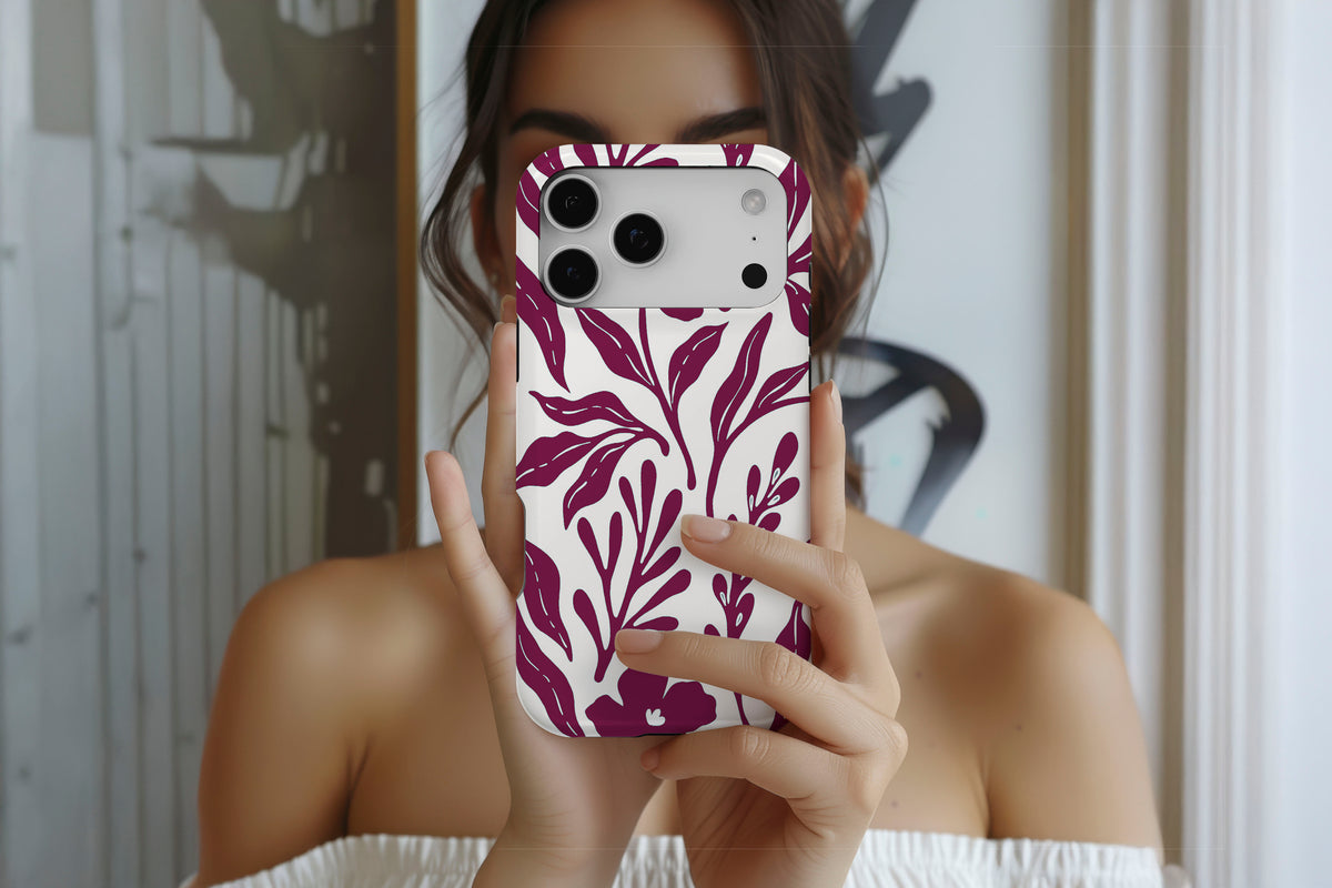 Lifestyle image of Matisse (Burgundy) MagTough phone case showing burgundy botanical line print on a cream base