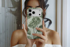 Lifestyle image of Sage Botanica MagTough phone case showing soft sage and eucalyptus green botanical floral print