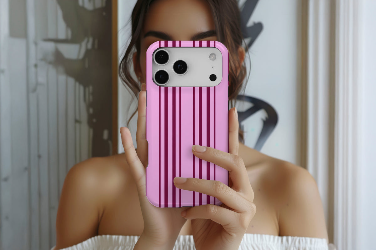 Lifestyle image of Sunday Club MagTough phone case showing pink and burgundy vertical stripe print
